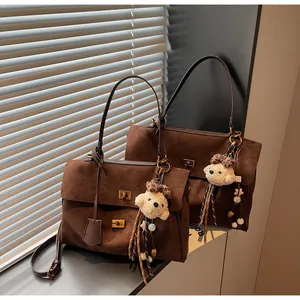 Detailed macro view of vintage brown suede tote bag featuring a cute plush bear keychain