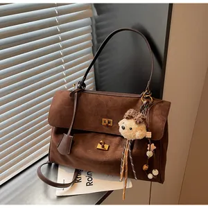 Detailed macro view of dark brown frosted suede handbag with gold buckles and charm