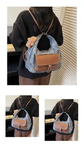 Detailed back view of a blue denim backpack with brown leather accents and bear charm.