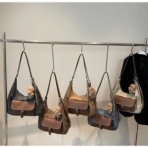 Multi-color large capacity hobo bags with teddy bear charms on a metal display rack.