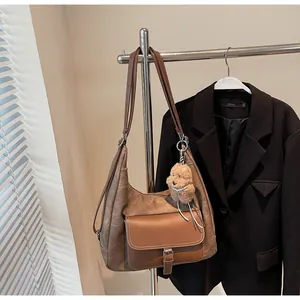 Large brown vintage-style tote bag hanging on a rack with a cute teddy bear charm