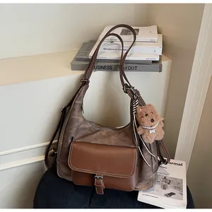 Detail view of large vintage brown tote bag featuring buckle pocket and plush dog charm