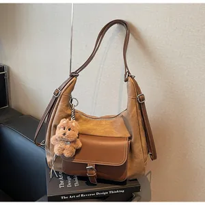 Large brown tote bag with a fuzzy dog charm resting on a book background