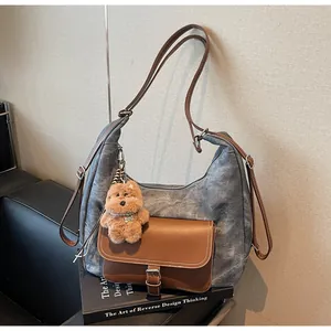 Large gray canvas tote bag with brown leather accents and plush dog charm on a book