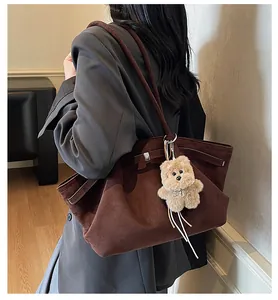 Detailed view of a large brown suede tote bag featuring a cute plush bear charm.