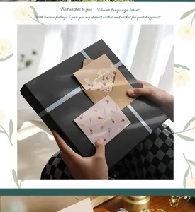 Manos sosteniendo una caja de regalo negra con tarjetas de felicitación y sobres