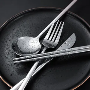 Premium silver stainless steel cutlery set with spoon, fork, knife and chopsticks on plate