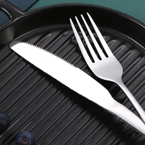 Premium stainless steel cutlery set with polished knife and fork on dark ribbed plate