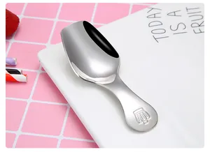 Close-up of polished stainless steel tea scoop with engraved handle design on white plate