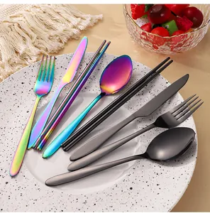 Close-up of iridescent and matte black stainless steel cutlery sets on a white plate