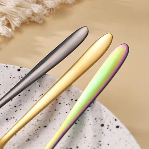 Detail of stainless steel cutlery set featuring black, gold, and iridescent pointed handles.