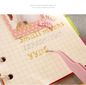 Detail of gold hot stamping alphabet stickers being applied to a grid journal page