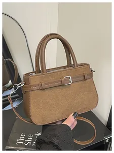 Close-up detail of a brown retro handbag featuring suede patchwork and a buckle