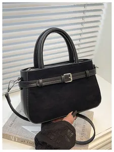 Detailed shot of a black suede handbag with belt buckle and leather handle