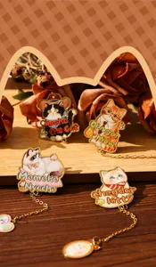 Close-up of four cute cartoon cat metal bookmarks with gold-plated chains and charms.