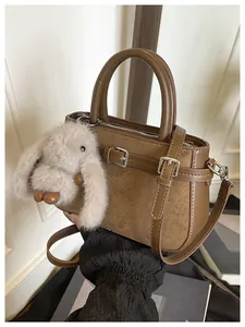 Detailed view of a brown vintage handbag featuring suede texture and a cute rabbit charm