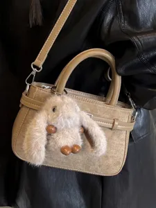 Vintage tan leather handbag with cute plush rabbit charm for women's daily commute.
