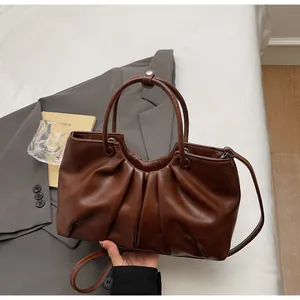 Primo piano di una borsa a mano vintage in morbida pelle marrone con eleganti pieghe.