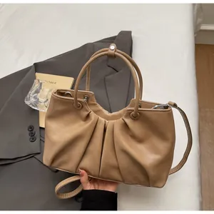 Dettaglio di una borsa a secchiello vintage in pelle morbida con manici e tracolla.