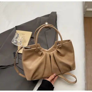 Vista dettagliata di una borsa a mano plissettata in morbida pelle beige con manici.