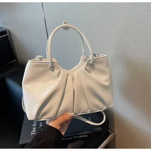 Dettaglio di una borsa a secchiello in morbida pelle bianca con design plissettato chic.