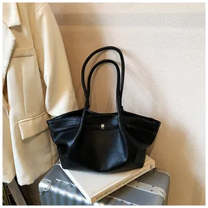 Borsa tote in pelle nera martellata posta su una valigia in un ambiente elegante