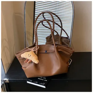 Elegante borsa tote in pelle marrone minimalista con un grazioso ciondolo a croissant