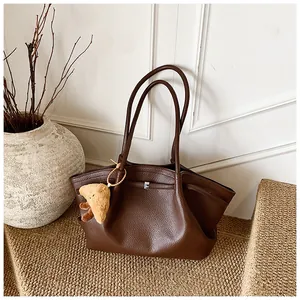 Vista dettagliata della borsa tote in pelle martellata marrone con ciondolo in peluche.
