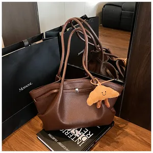 Vista dettagliata di una borsa tote in pelle marrone dal design minimal e ciondolo a cornetto