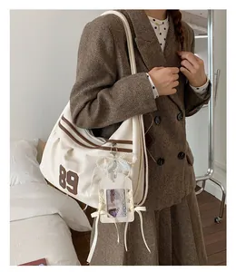 Grande borsa tote in tela beige con stampa '89' marrone indossata da una modella chic