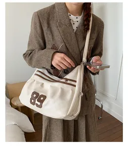Grande borsa tote crema con toppa 89 indossata da modella in completo marrone.