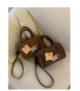 Vintage brown suede Boston handbags with leopard print and cute charms on a white sofa.