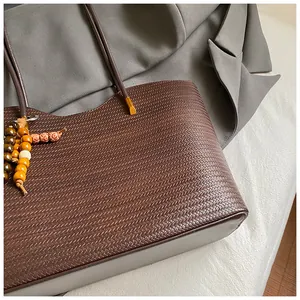 Detailed close-up showing the brown woven texture of a large capacity tote bag with beads.