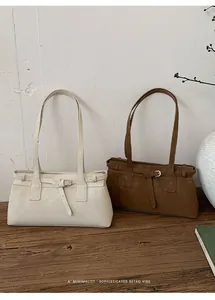 Zwei minimalistische Retro-Schultertaschen in Weiß und Braun auf einem rustikalen Holztisch