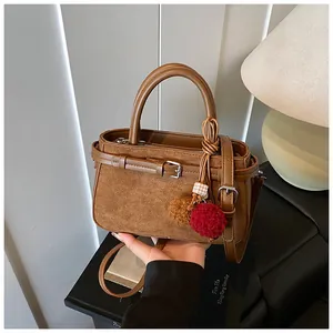 Vintage brown suede handbag detail with pom-pom charm and belt buckle design