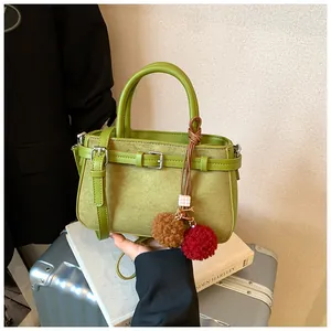 Green matte suede retro handbag featuring buckle details and colorful fuzzy pom-pom charms