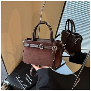 Close-up view of a retro dark brown frosted handbag with silver buckle decorative straps