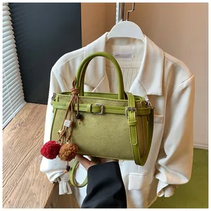 Retro green suede handbag with decorative pom-pom charm and elegant top handle strap