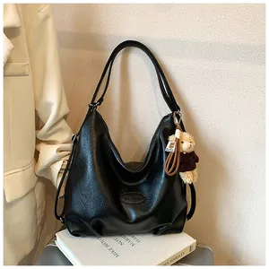 Vista dettagliata di una borsa tote retrò in pelle nera con un simpatico ciondolo a orsetto