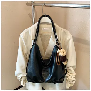 Vista dettagliata di una borsa hobo vintage nera con un ciondolo a forma di orsetto