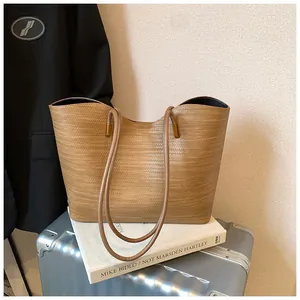 Detailed view of tan woven texture large capacity tote bag on a lifestyle prop