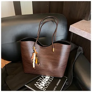 Detail of a brown woven tote bag on a black leather chair with a magazine prop.