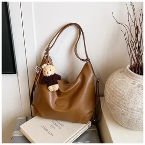 Foto lifestyle di borsa hobo multifunzionale marrone vintage con ciondolo a forma di orsetto.