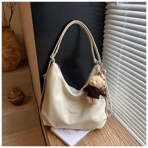 Elegante borsa tote vintage in pelle crema con ciondolo a forma di orso in un interno