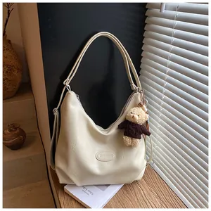 Primo piano di una borsa tote pendolare in ecopelle crema con un simpatico orsetto