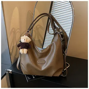 Dettaglio di una borsa tote vintage marrone multifunzionale con ciondolo orsetto