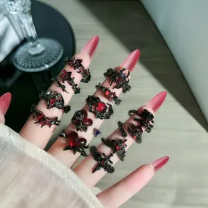Primer plano de anillos góticos con motivos de espinas rojas, murciélagos y cruces