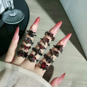 Vista detallada de anillos góticos con piedras rojas y diseños de murciélago y espinas.