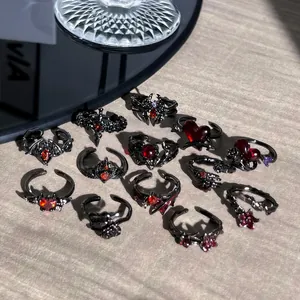 Set de joyas góticas con anillos de metal oscuro, gemas rojas, murciélagos y corazones
