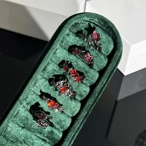 Detalle de anillos góticos con murciélago y flores, cristales rojos en caja verde